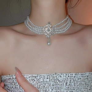 Détail d'un collier ras de cou à quatre rangs de perles blanches et pendentif en cristal