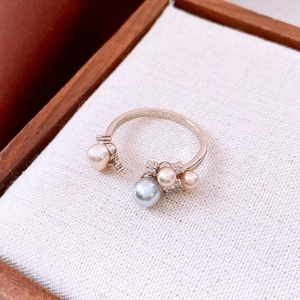Macro shot of rose gold ring with grey-blue pearl and zircon accents on white fabric