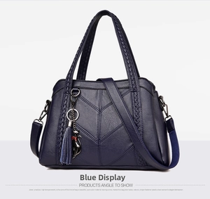 Detail of navy blue leather tote bag showing woven handles and cute cat charm tassel