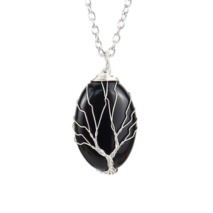 Detail of life tree wire wrapped pendant with oval black stone on silver chain
