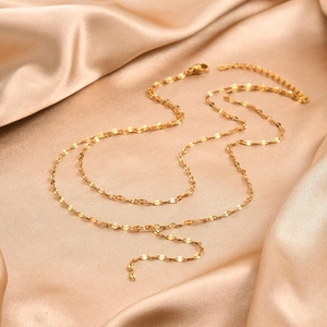 Detail of 18K gold lip chain necklace with lobster clasp on silk satin background