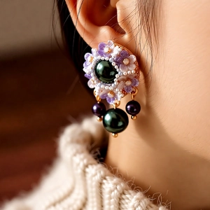 Detailed macro view of vintage pearl drop earrings with purple floral design details