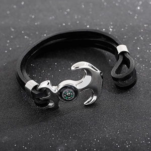 Macro detail of men's leather anchor bracelet featuring a built-in functional compass dial