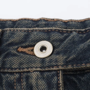 Detalle de botón metálico y costuras en contraste en vaqueros barrel azul oscuro
