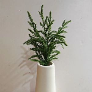 Realistic Norfolk pine branch in white ceramic vase for Christmas holiday home decoration