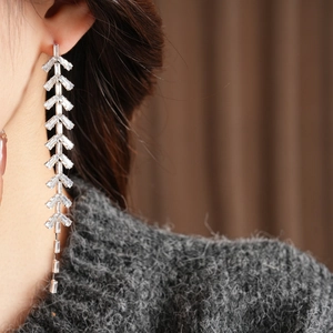 Close-up of dangling silver leaf tassel earrings with sparkling zircon crystals on a model
