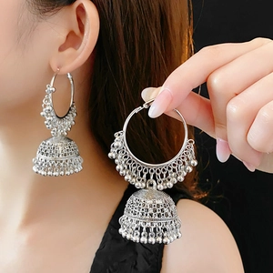 Macro shot of silver Indian Jhumka earrings with vintage bell charms on a model