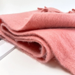 Detailed close-up of soft pink mohair wool scarf with fringe and fluffy texture