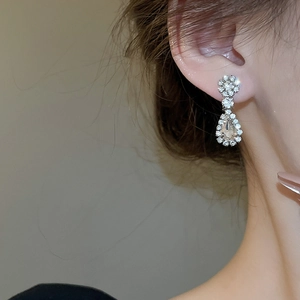Close-up of elegant champagne teardrop earrings with silver-toned diamond settings