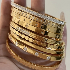 Close-up of golden stainless steel bangles with star patterns and zircon stone details