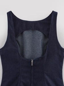 Détail du dos d'un gilet en jean bleu foncé avec découpe évidée et fermeture éclair arrière