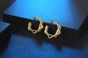 Macro detail of golden multi-layered geometric earrings on navy textured display
