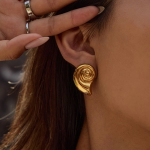 Elegant gold spiral seashell earrings in stainless steel on model for a resort look