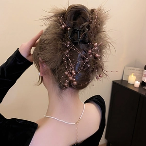 Detail of coffee brown feather hair claw clip with pearls on elegant updo hairstyle