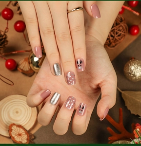 Close-up of Christmas press-on nails with reindeer patterns and silver glitter accents