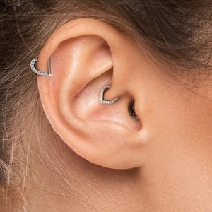 Macro shot of V-shaped S925 silver cartilage piercings with clear gemstones on ear