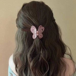 Pink translucent butterfly hair claw clip worn by a model in a natural setting