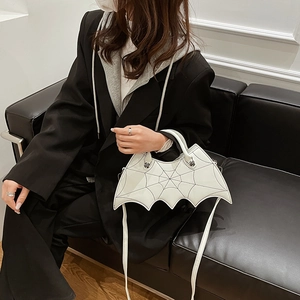 Detailed view of a white bat-shaped handbag featuring spiderweb stitching and skull studs