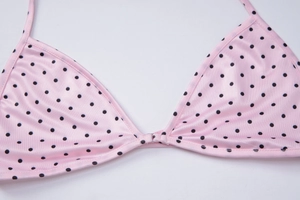 Detailed view of pink bikini top with black polka dots and halter neck straps