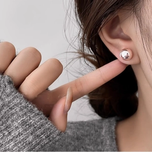 Close-up of elegant rose gold pearl stud earrings worn by a model in a side profile view