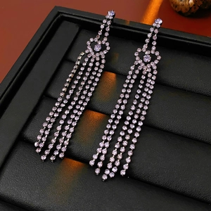 Vue macro de boucles d'oreilles pampilles en argent avec cœur et strass violets
