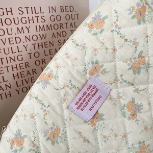 Detailed macro of floral quilted cotton makeup bag showing soft texture and fine stitching