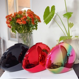 Three glossy egg-shaped metal clutch bags in black, red, and iridescent mirror finish