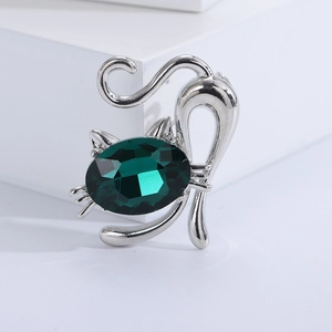 Close-up of a silver cat brooch with a large dark green oval gemstone on white background