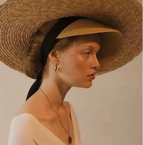 Détail de boucles d'oreilles créoles dorées en titane portées par un mannequin sous une lumière chaude