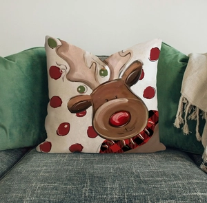 Close-up of a Christmas reindeer decorative pillow on a gray sofa with cozy holiday decor