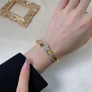 Elegant gold heart-shaped spring open bangle with sparkling diamonds on satin background