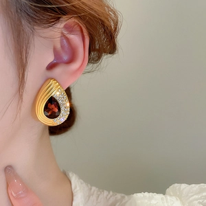 Close-up of teardrop earring with red gemstone and small diamonds on a female model