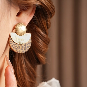 Close-up of elegant gold metal earrings with leopard print discs on a model