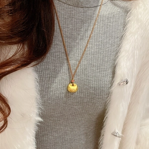 Detailansicht einer goldfarbenen Halskette im chinesischen Stil am Hals eines Models