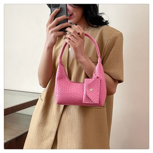 Close-up of pink woven texture handbag held by model with matching coin purse charm