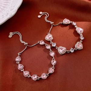 Detailed view of rose gold zircon heart bracelets on elegant dark silk background