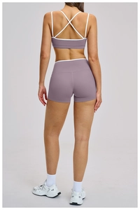 Detail of cross-back sports bra and high-waisted shorts set in smoky pink and purple