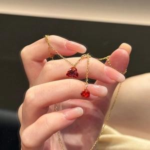 Detailed view of a gold-tone necklace featuring two sparkling red heart crystals