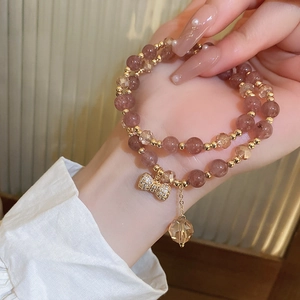 Detail of pink crystal beaded double-layer bracelet with gold bow and heart charms