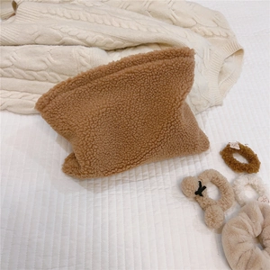 Detailed close-up of brown teddy fleece makeup bag texture on a white quilted background