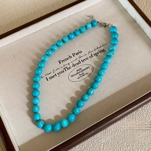 Close-up of turquoise beaded necklace with silver lobster clasp on a beige tray