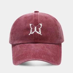 Close-up of white butterfly embroidery on a vintage washed cotton burgundy baseball cap