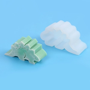 Détail d'un moule en silicone blanc et d'une figurine de stégosaure vert sur fond bleu
