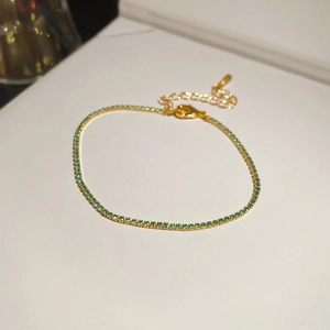 Close-up of gold tennis bracelet with green zircon stones and lobster clasp closure
