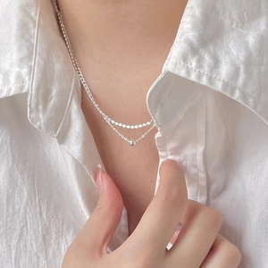 Close-up of a minimalist S925 sterling silver layered necklace on a white shirt