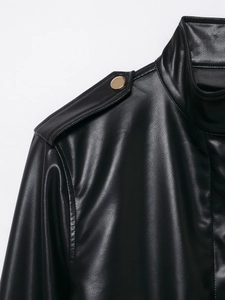 Detail einer schwarzen Kunstlederjacke mit goldenen Knöpfen und Textur-Finish