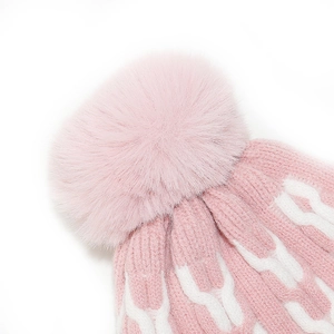 Close-up of pink knit winter hat with white weave pattern and large fluffy pompom detail