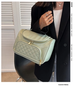Detailed view of the light green quilted cosmetic bag with gold hardware and top handle.