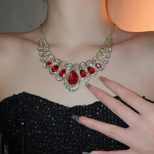 Detail of vintage gold necklace with red teardrop gems and crystals on a model