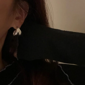 Detail view of sterling silver geometric drop earrings with polished irregular twisted design
